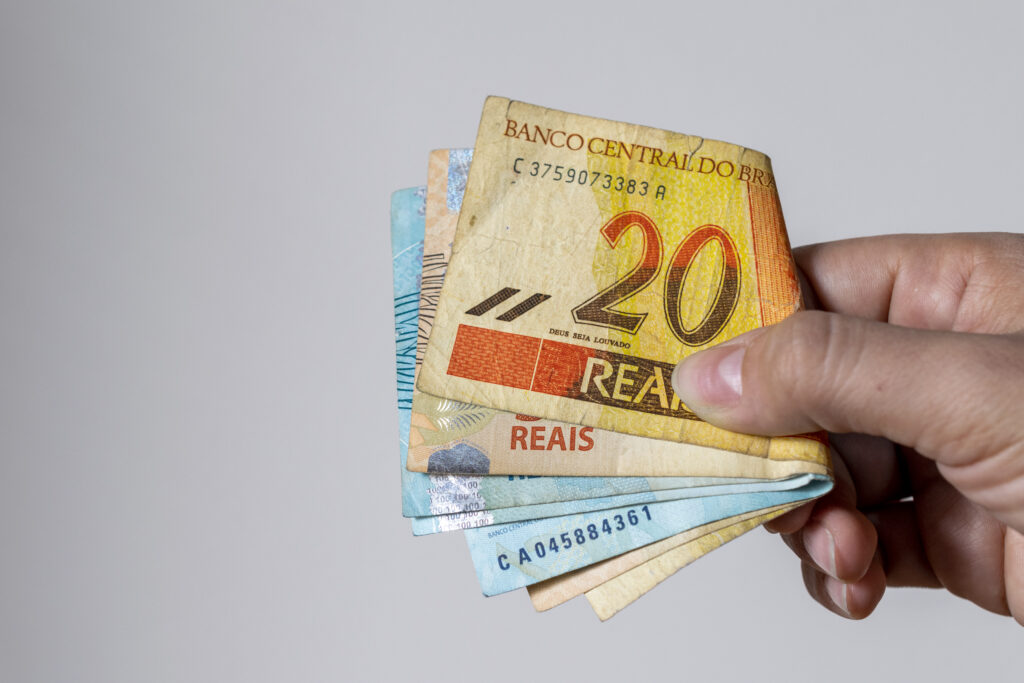 woman holding used brazilian money banknotes